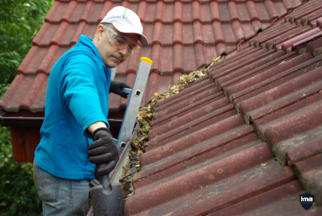 Man cleaning out the gutter on the roof of a home